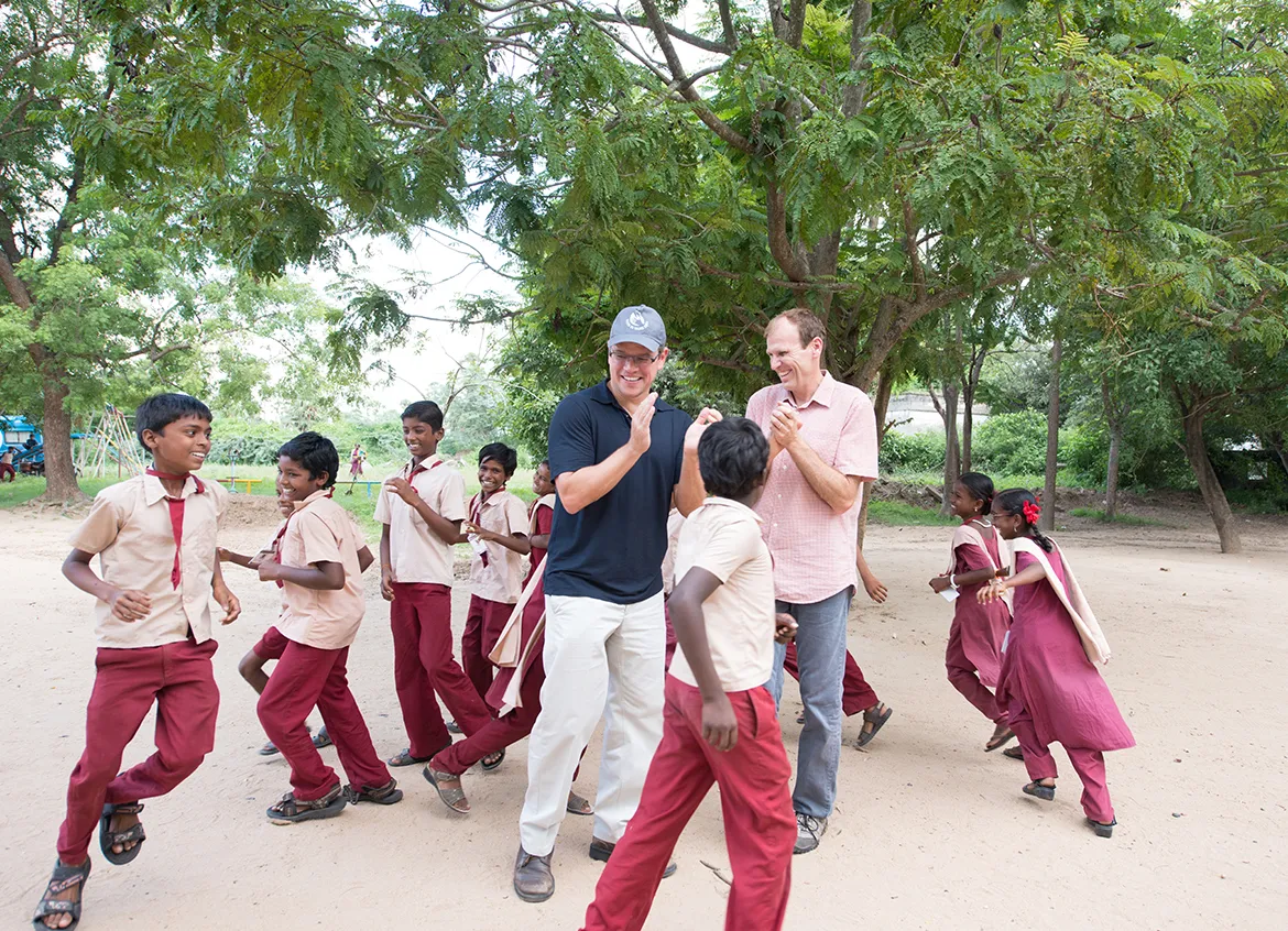 Water.org co-founders Gary White and Matt Damon joining children during playtime at school.