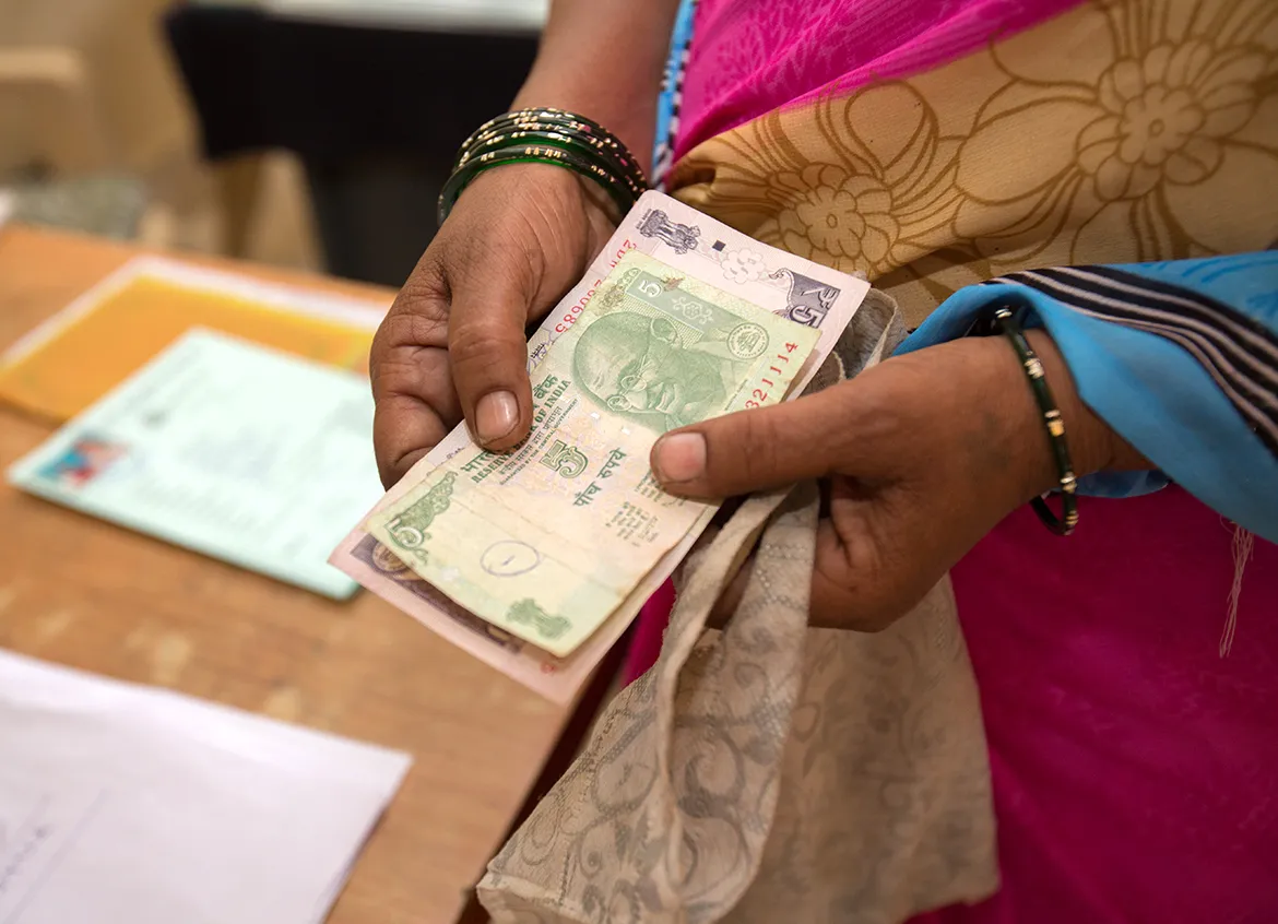 Woman holding Indian rupees to pay for her WaterCredit solution.