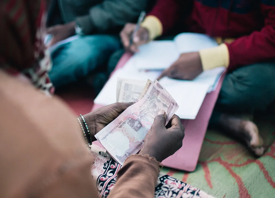 Woman counting rupees to pay for her WaterCredit solution.