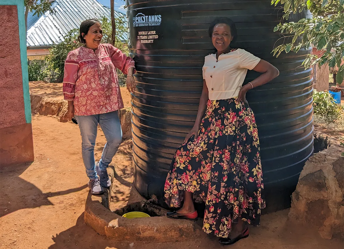 Two women smiling in front of a water tank.