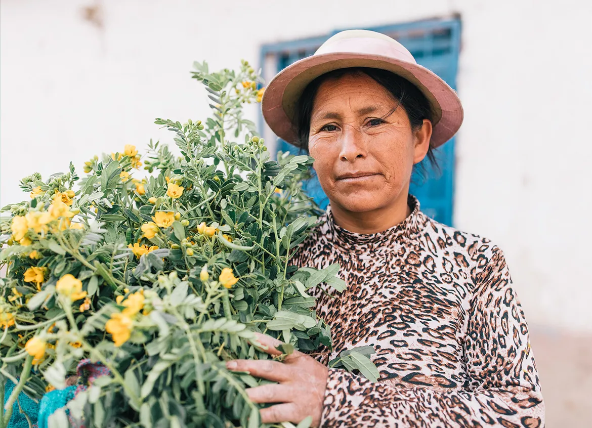 A woman in Peru holds yellow flowers at a market.