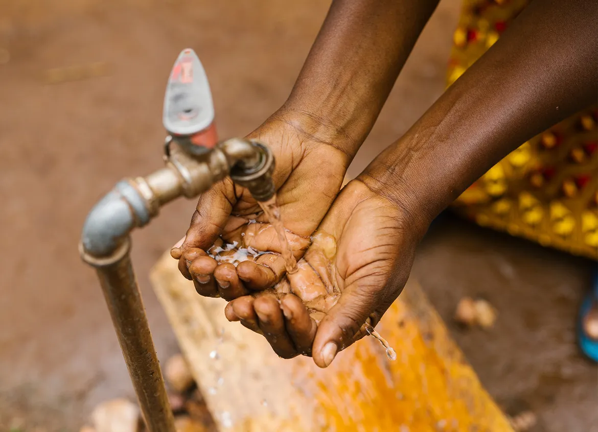 A woman washes her hands in water flowing from a tap.