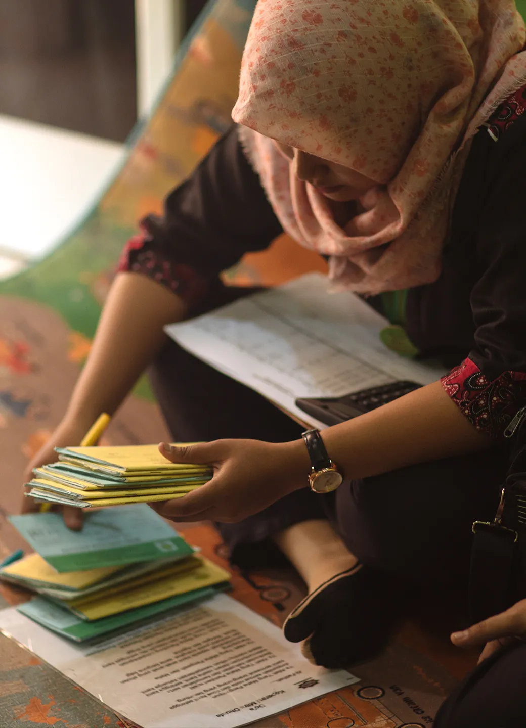 Woman who works at Water.org partner organization sifting through financial documents.