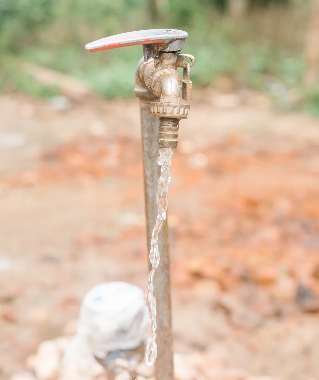 Water spout with red handle dispensing a stream of safe water.