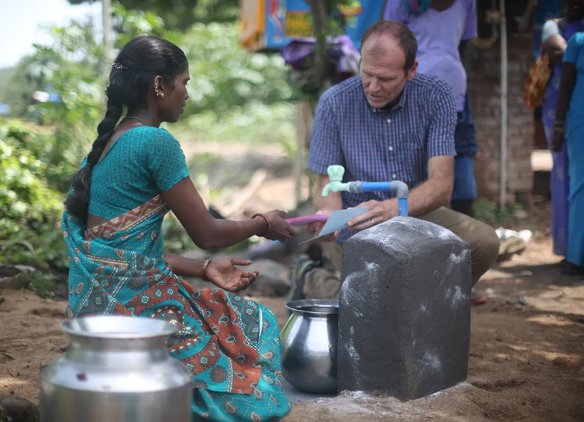 Gary White exchanging WaterCredit documents with a woman in India.