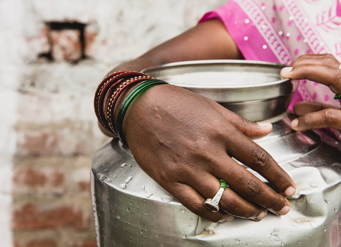 Woman holds a silver water vessel in India.